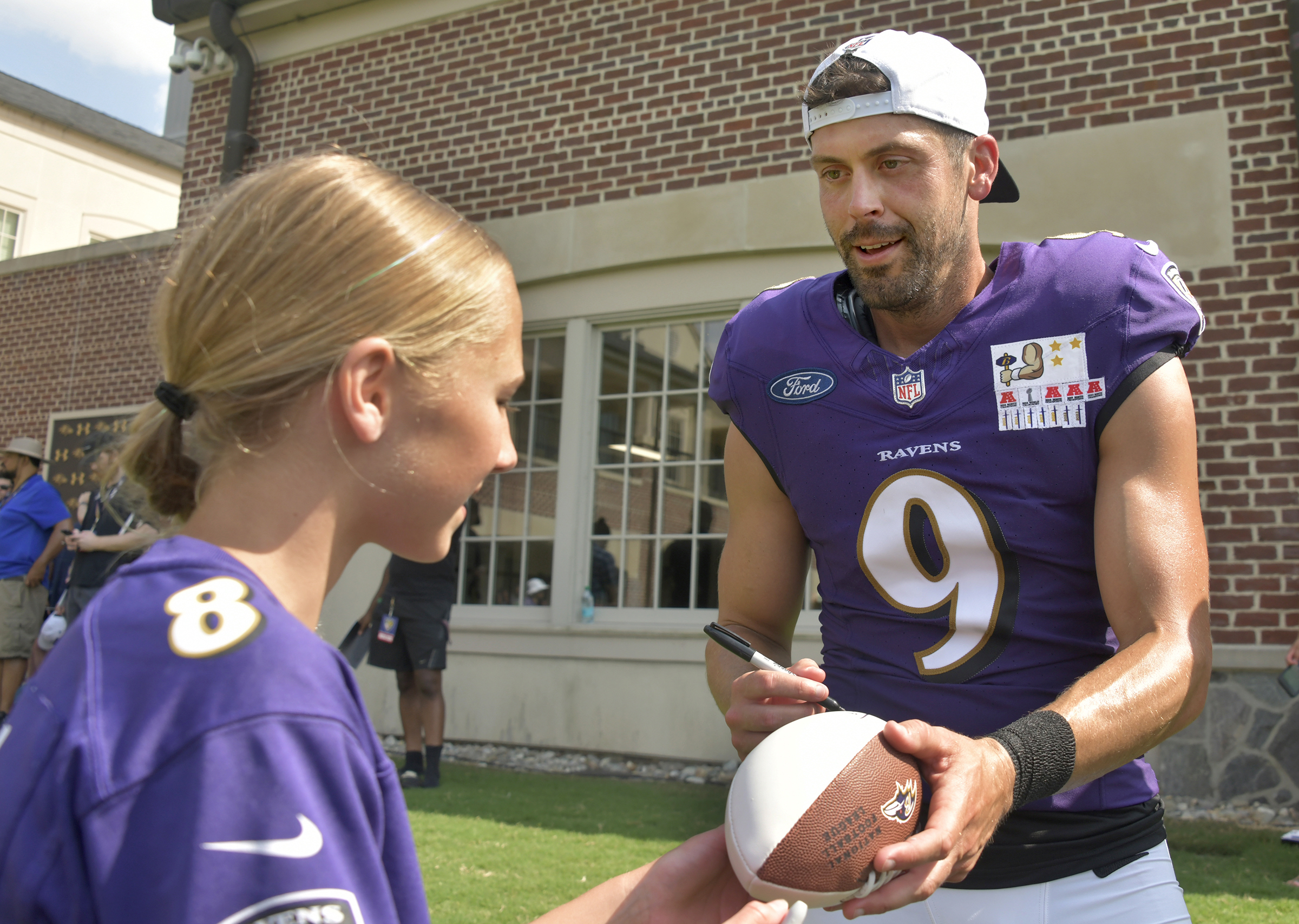 Kicker Justin Tucker signs a football for Madeline Hammond, 13,...