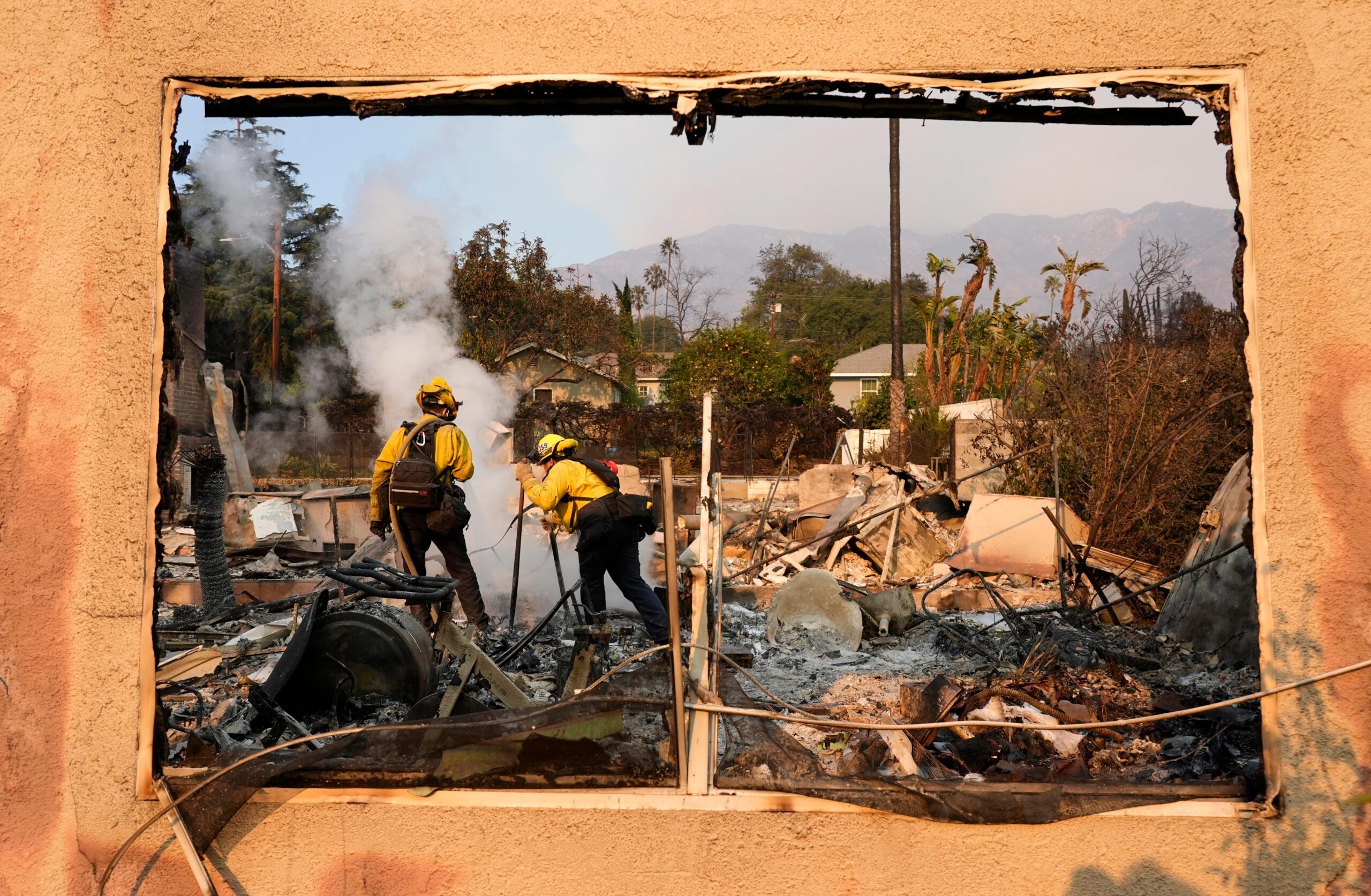 Firefighters extinguish burning embers at a house on Santa Rosa...